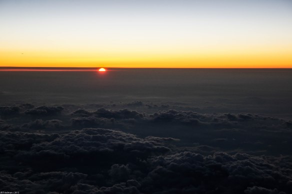 the sun sets over the clouds